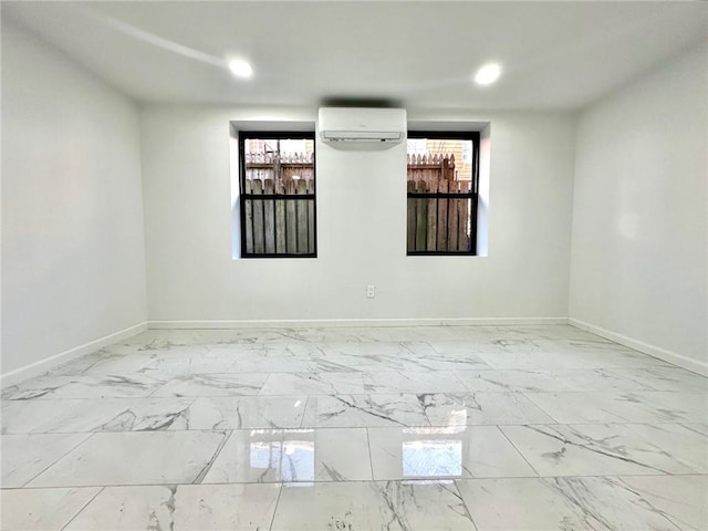 empty room featuring an AC wall unit, baseboards, and marble finish floors