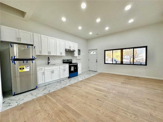 kitchen featuring electric range, freestanding refrigerator, open floor plan, under cabinet range hood, and white cabinetry