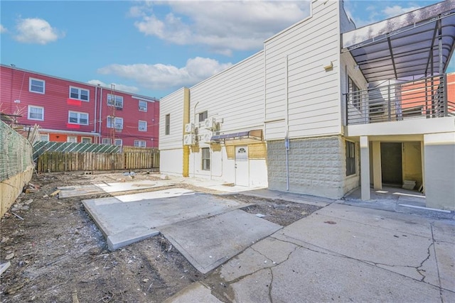 rear view of house with a balcony, a patio area, and fence