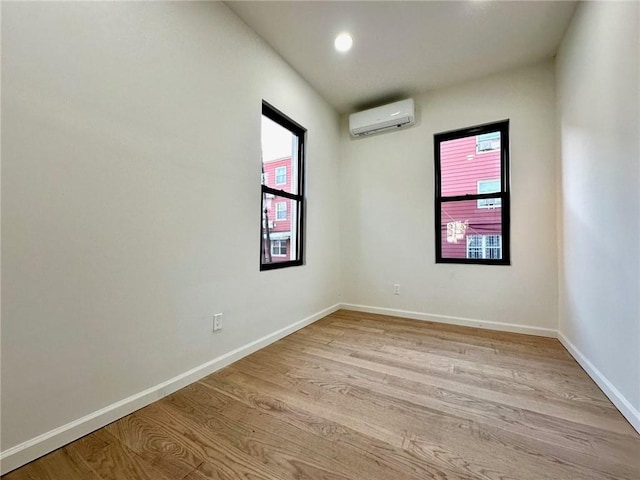 spare room featuring an AC wall unit, light wood finished floors, baseboards, and recessed lighting