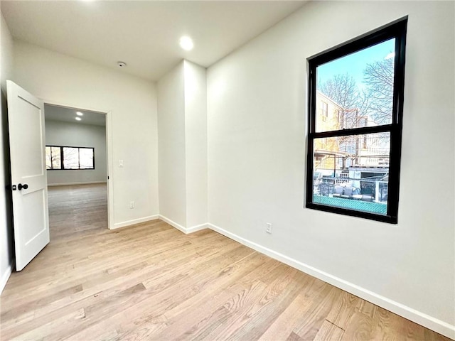 unfurnished room with light wood-type flooring and baseboards