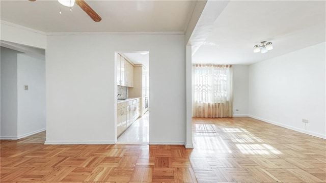 unfurnished room with ceiling fan, crown molding, and baseboards