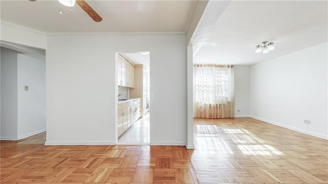 unfurnished room featuring crown molding, baseboards, a ceiling fan, and a sink
