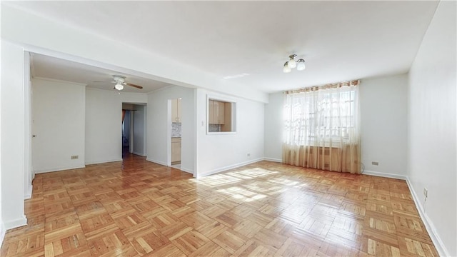 spare room with crown molding, baseboards, and ceiling fan