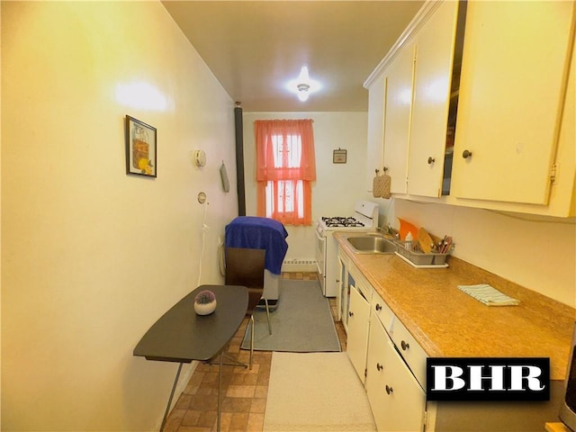 kitchen featuring white gas range, white cabinetry, light countertops, light floors, and a sink