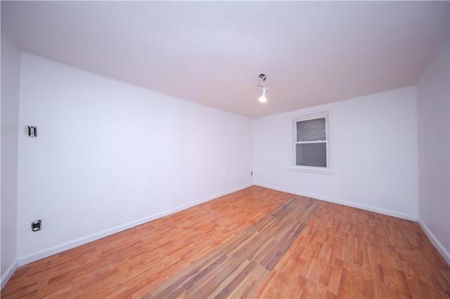 spare room featuring baseboards and light wood-style floors