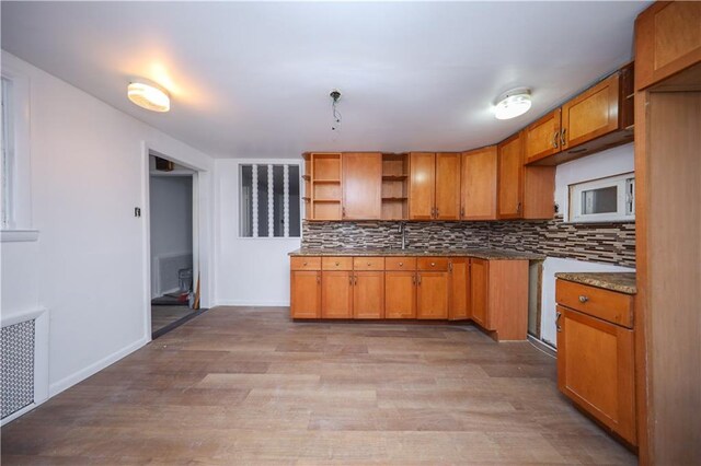 kitchen featuring radiator, decorative backsplash, sink, and light hardwood / wood-style floors