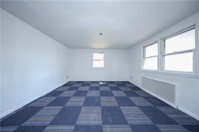 unfurnished room with radiator and dark carpet