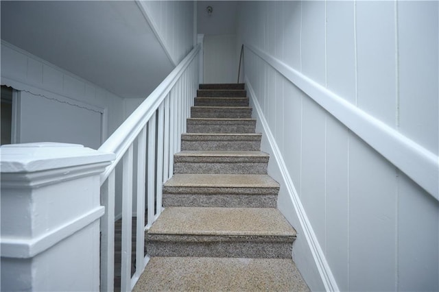 stairs featuring a decorative wall and speckled floor