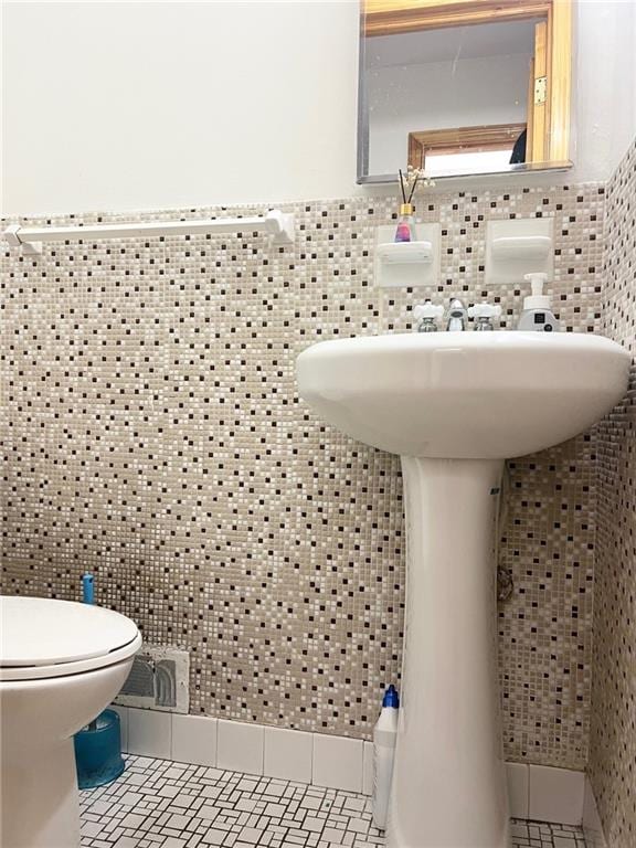 bathroom with tile patterned flooring, tile walls, and toilet