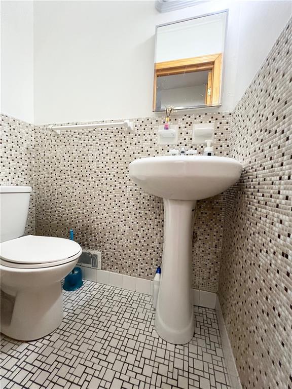 bathroom with toilet and tile walls