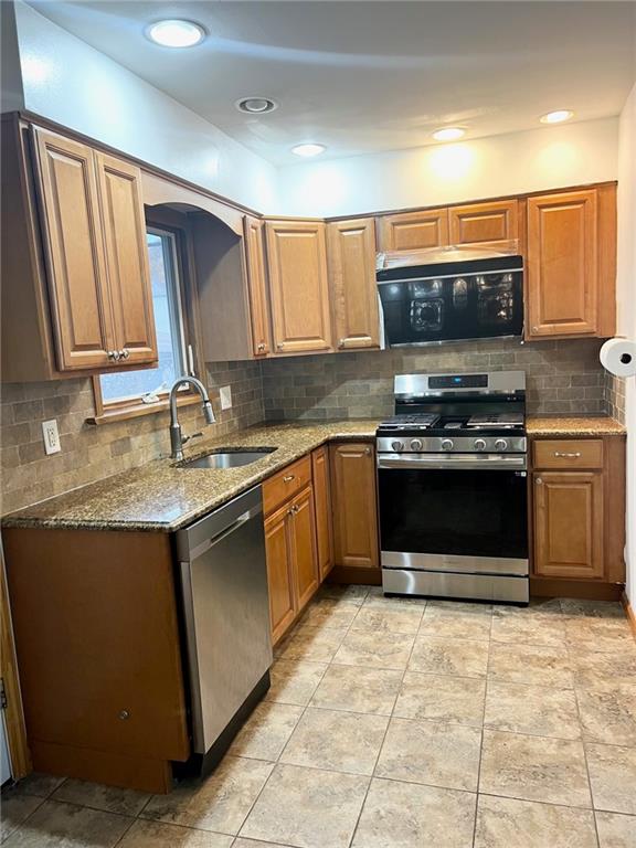 kitchen featuring light stone countertops, sink, appliances with stainless steel finishes, and tasteful backsplash