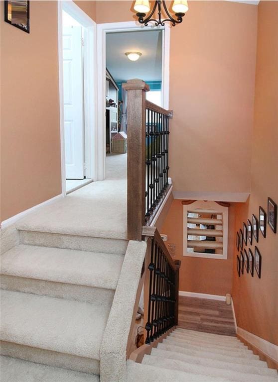 stairway with wood-type flooring and a chandelier