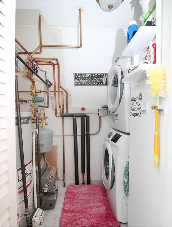 clothes washing area with stacked washer and dryer and water heater