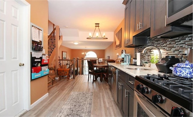 kitchen featuring pendant lighting, a notable chandelier, light wood-type flooring, and dark brown cabinetry