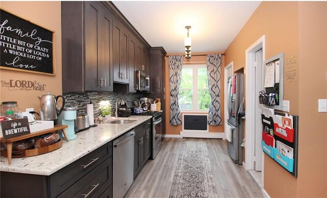 kitchen with decorative backsplash, appliances with stainless steel finishes, dark brown cabinetry, and light hardwood / wood-style floors