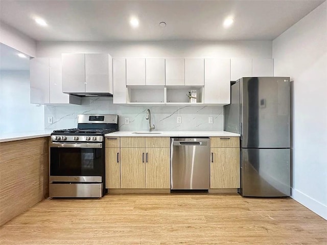 kitchen featuring a sink, light wood-type flooring, open shelves, and appliances with stainless steel finishes