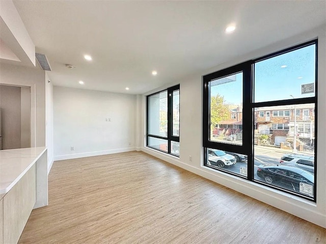 spare room with a wall of windows and light wood-type flooring