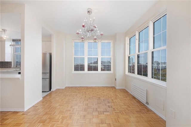 unfurnished dining area with plenty of natural light, baseboards, and a chandelier