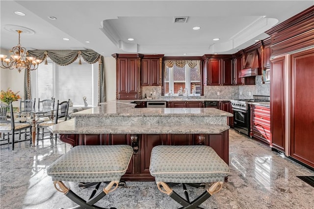 kitchen with an inviting chandelier, backsplash, pendant lighting, high end range, and custom exhaust hood