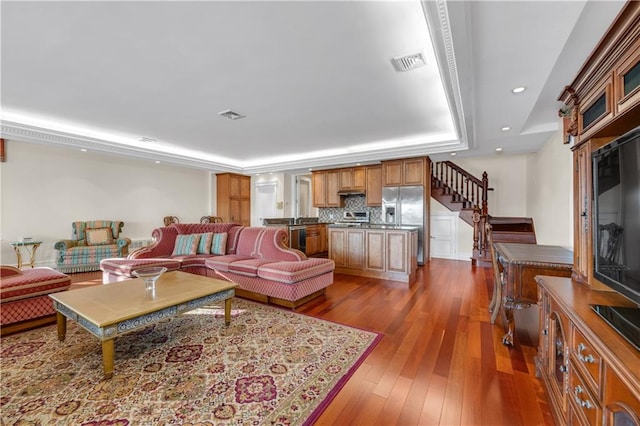 living room with dark wood-type flooring and a tray ceiling