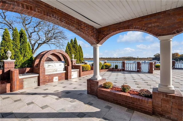 view of patio with a water view and exterior kitchen