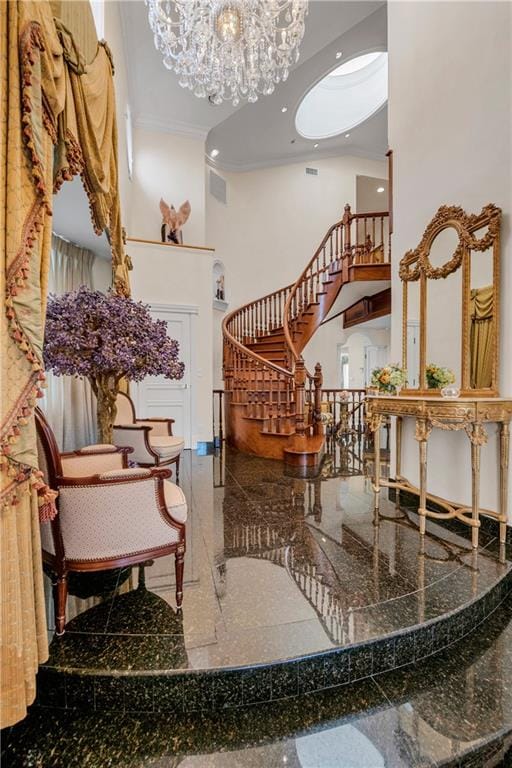 interior space with a towering ceiling, crown molding, and an inviting chandelier