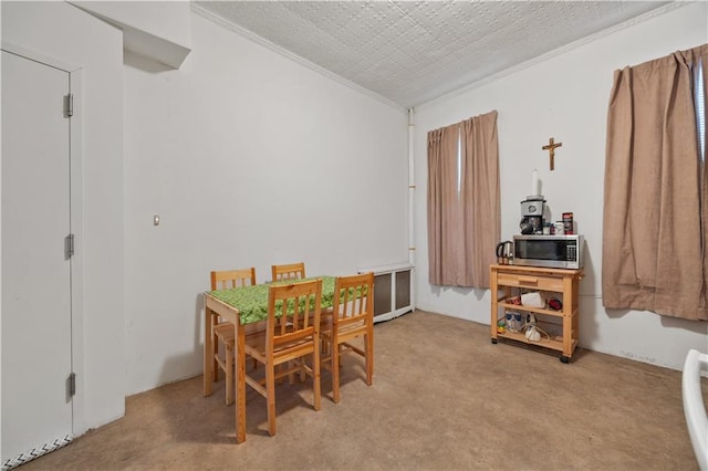 dining room featuring light colored carpet, ornamental molding, and a textured ceiling