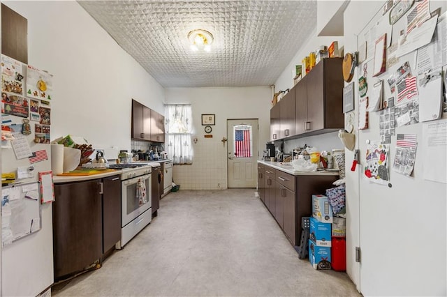 kitchen featuring dark brown cabinets, white refrigerator, and gas stove