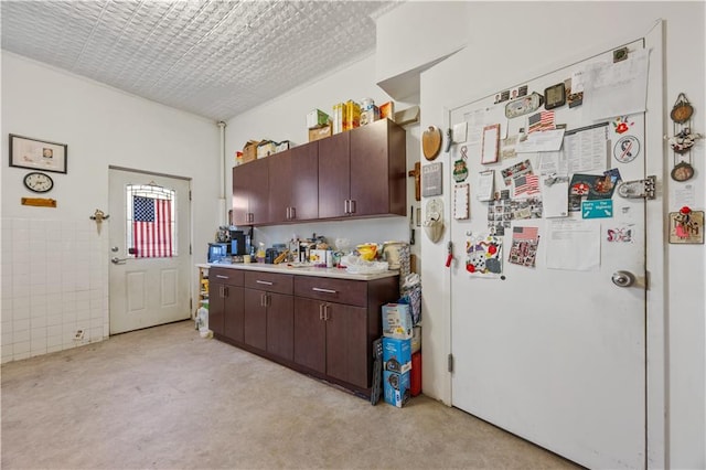 kitchen featuring dark brown cabinetry, white refrigerator, and tile walls