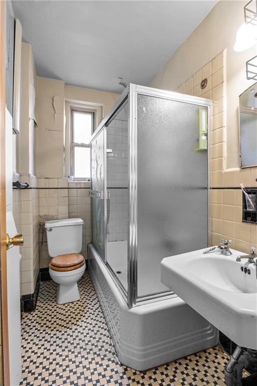 bathroom with tile walls and toilet