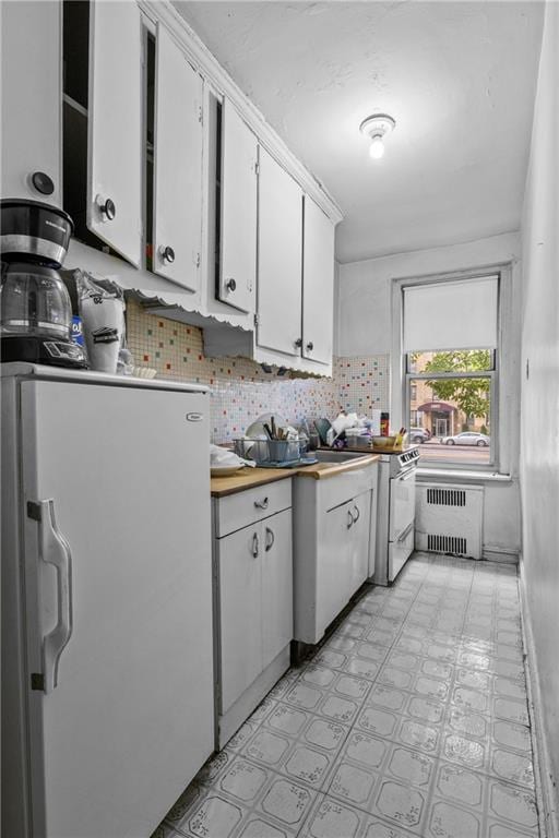 kitchen with tasteful backsplash, white cabinetry, radiator heating unit, and white appliances