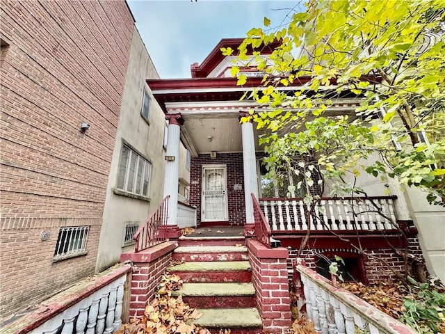 entrance to property with brick siding and a porch