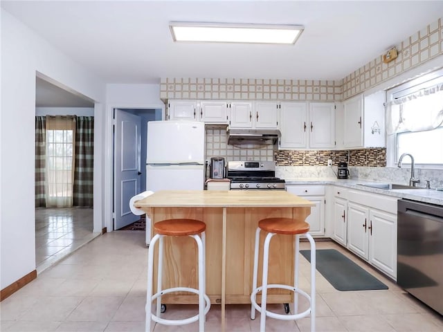 kitchen with white cabinetry, sink, stainless steel appliances, wood counters, and a kitchen breakfast bar