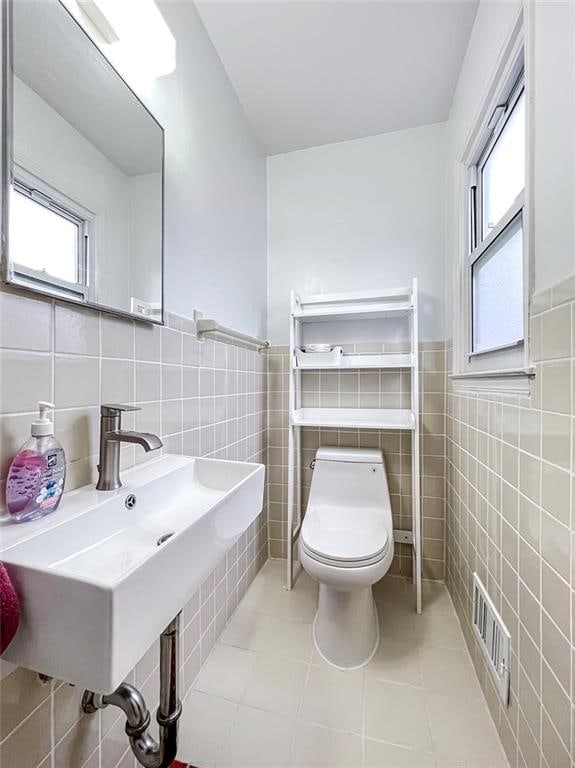 bathroom with tile patterned flooring, sink, toilet, and tile walls