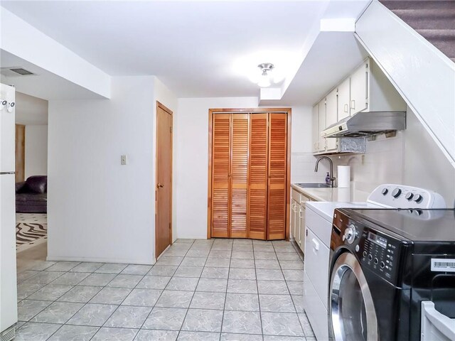 washroom with washer and clothes dryer, sink, light tile patterned floors, and cabinets