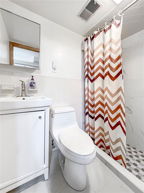 bathroom featuring a shower with curtain, toilet, tile walls, and vanity