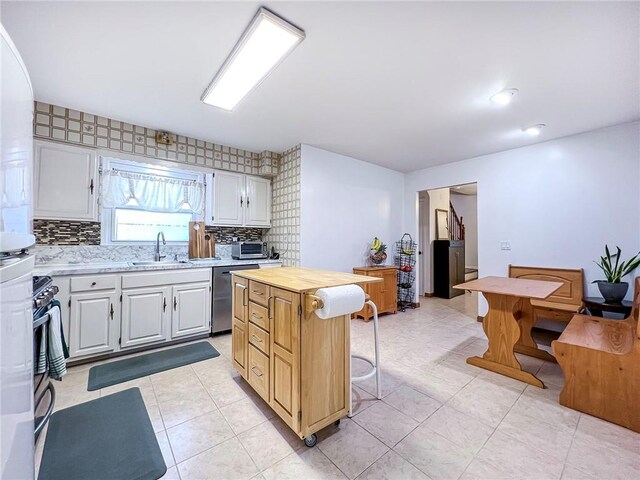 kitchen with dishwasher, a center island, wooden counters, sink, and white cabinetry