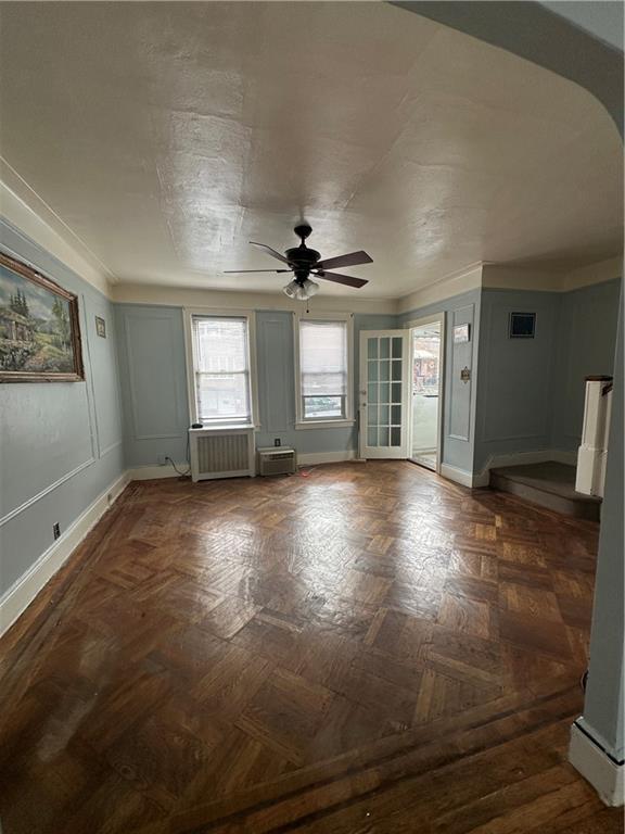 unfurnished room with radiator heating unit, dark parquet floors, and ceiling fan