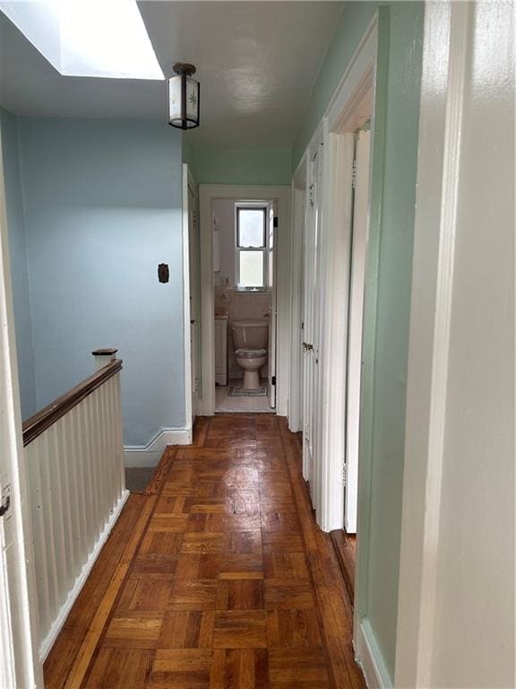 hall featuring dark parquet flooring and a skylight