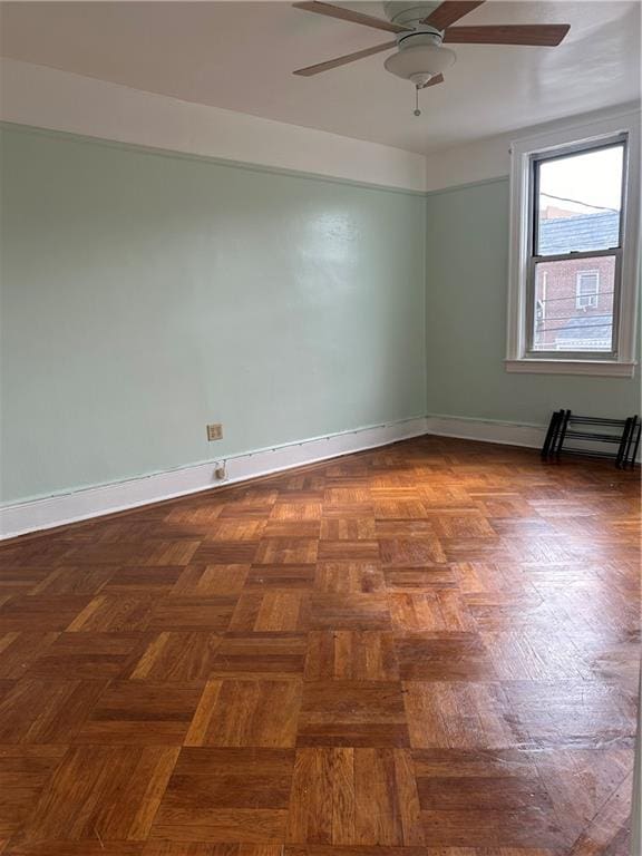 spare room featuring ceiling fan and dark parquet floors