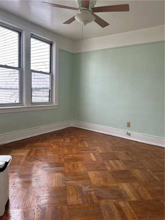 empty room with ceiling fan and dark parquet flooring