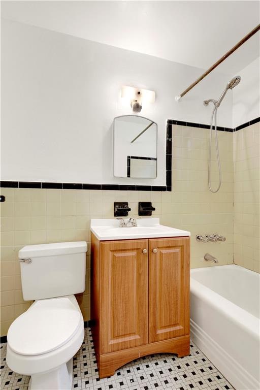 35 Oliver St Unit 1D, Brooklyn, NY 11209 - full bathroom featuring vanity, tile walls, shower / bath combination, toilet, and wainscoting