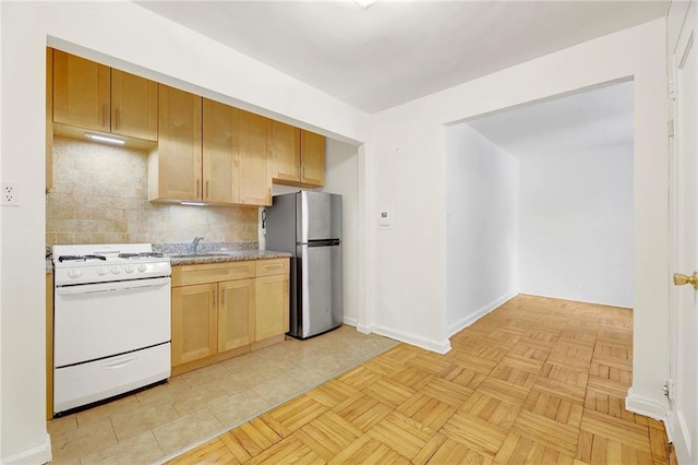 35 Oliver St Unit 1D, Brooklyn, NY 11209 - kitchen featuring white gas stove, freestanding refrigerator, tasteful backsplash, baseboards, and ventilation hood