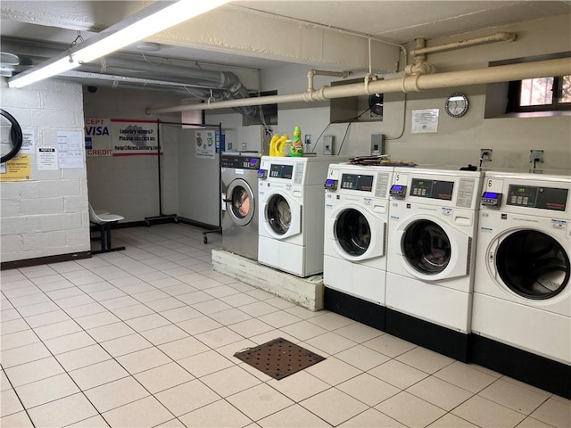 community laundry room with concrete block wall and independent washer and dryer