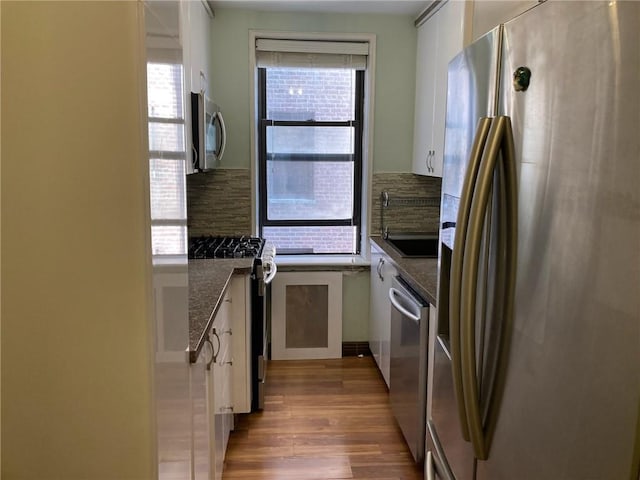 kitchen with stainless steel appliances, sink, dark stone countertops, and white cabinets