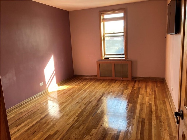 spare room featuring baseboards and wood finished floors