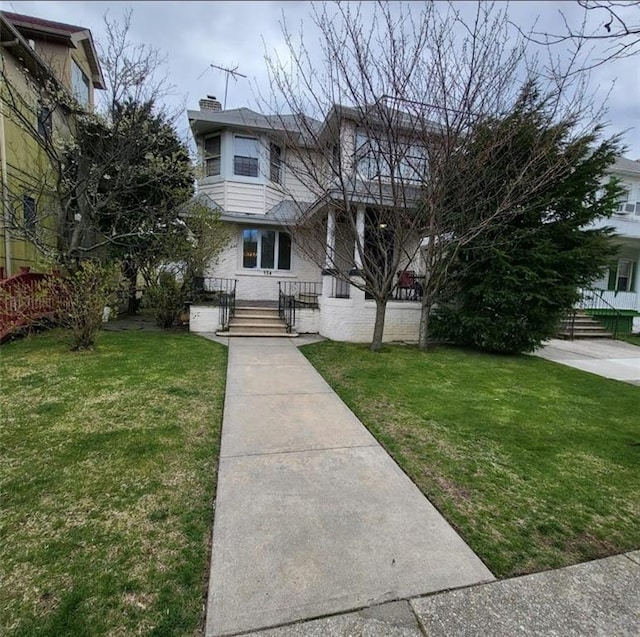 view of front of home with a chimney, brick siding, and a front yard