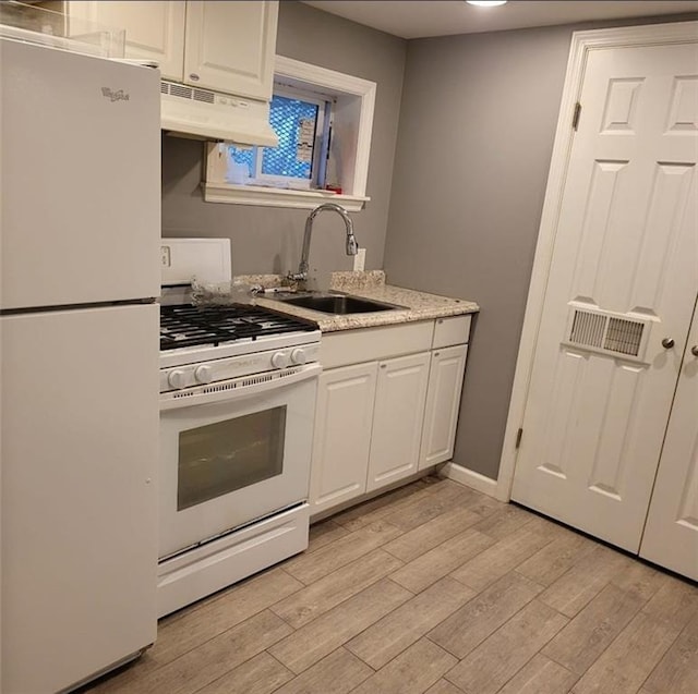 kitchen featuring a sink, under cabinet range hood, light countertops, white cabinets, and white appliances