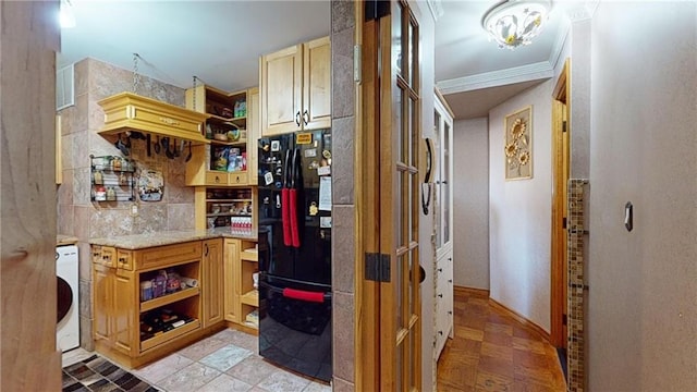 kitchen with black refrigerator, washer / clothes dryer, and ornamental molding